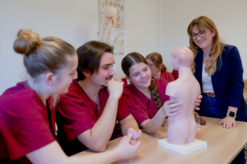 Schüler im Pflegekolleg beim Unterricht mit einem Modell des menschlichen Körpers